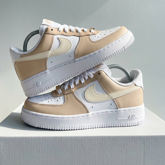 Pair of beige and white sneakers stacked on a light gray background
